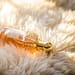 Elegant perfume bottle with gold details resting on fluffy white fur, capturing luxury and glamour.