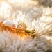 Trendi parfumov leta 2025 6 Elegant perfume bottle with gold details resting on fluffy white fur, capturing luxury and glamour.